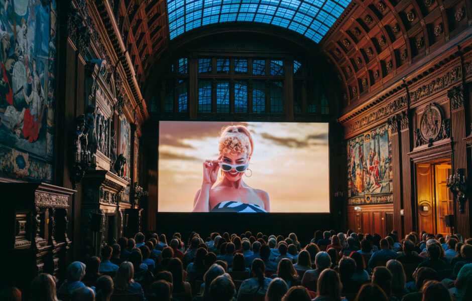 Das Publikum sitzt vor der Leinwand und sieht den Film Barbie in der Oberen Halle