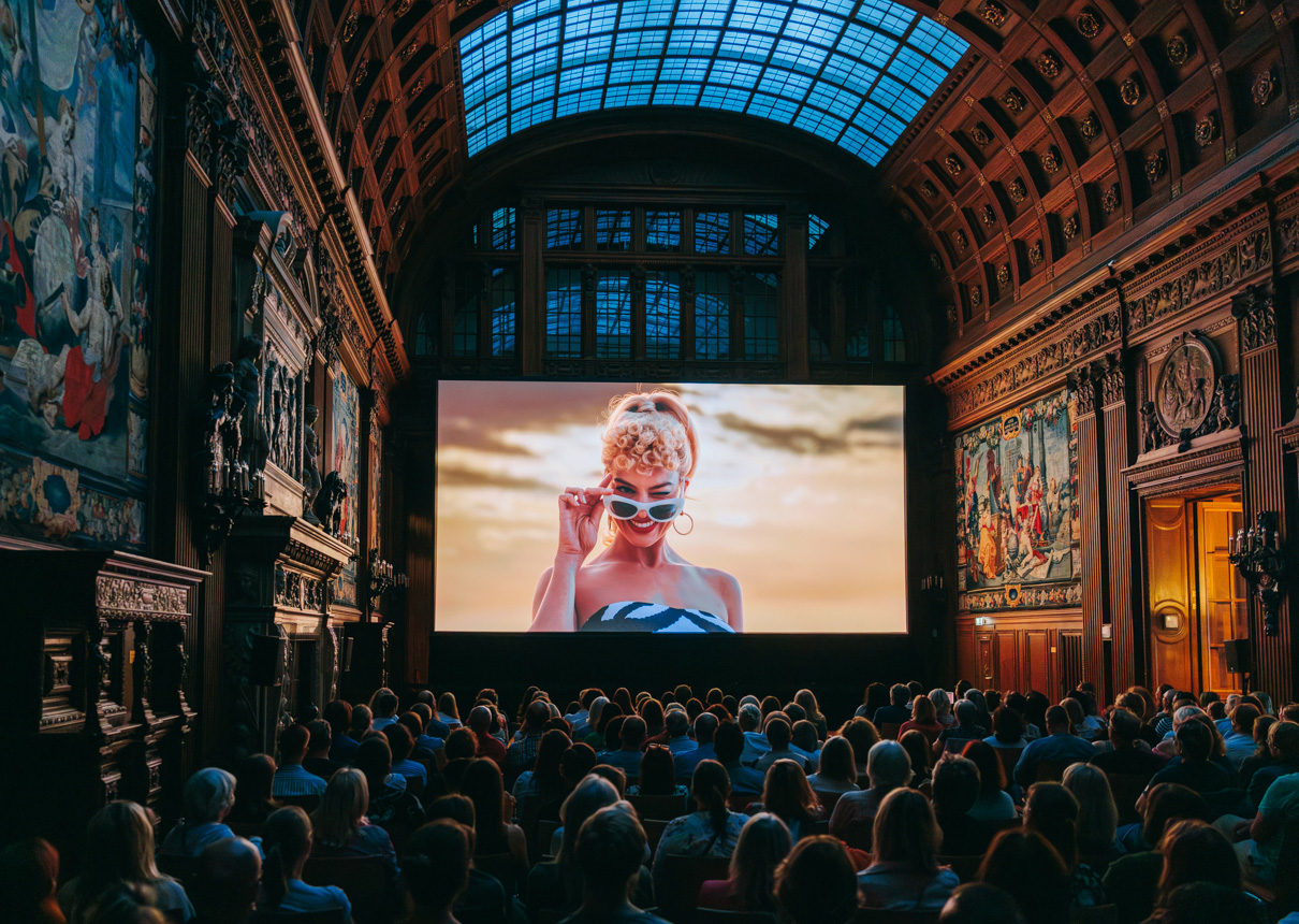 Das Publikum sitzt vor der Leinwand und sieht den Film "Barbie" in der Oberen Halle