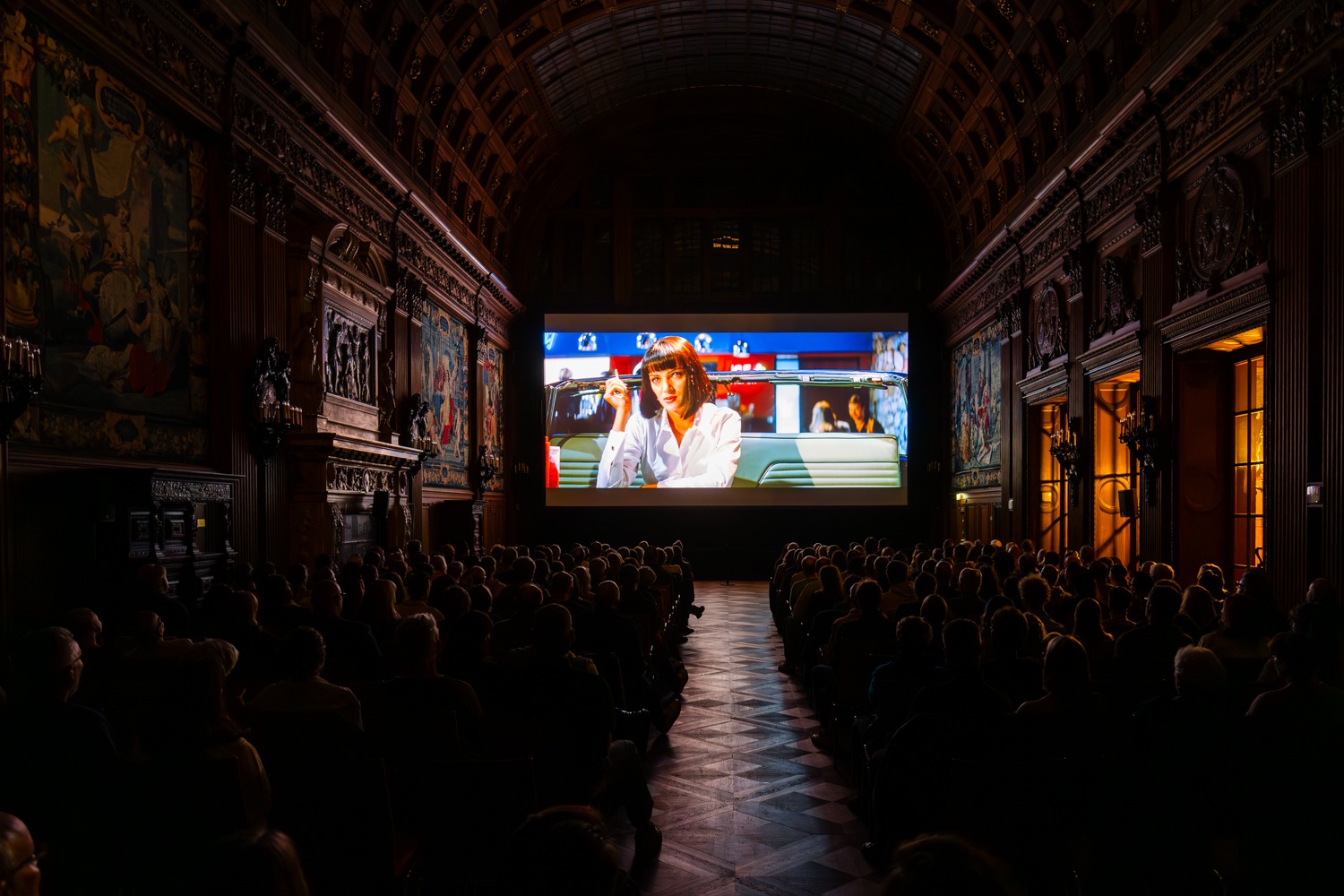 Kino in der Oberen Halle: Uma Thurman ist auf der Leinwand im Film Pulp Fiction zu sehen. Das Publikum sitzt davor.