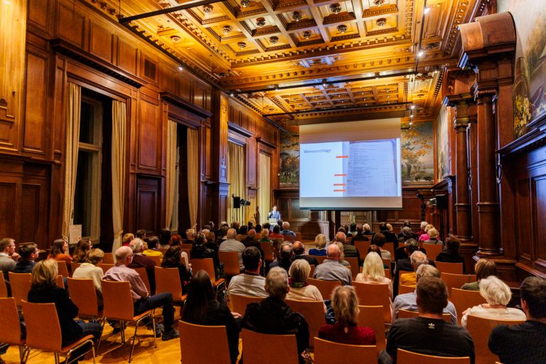 Das Publikum sitzt im Speisesaal der Villa Hügel und hört dem Vortragenden zu.