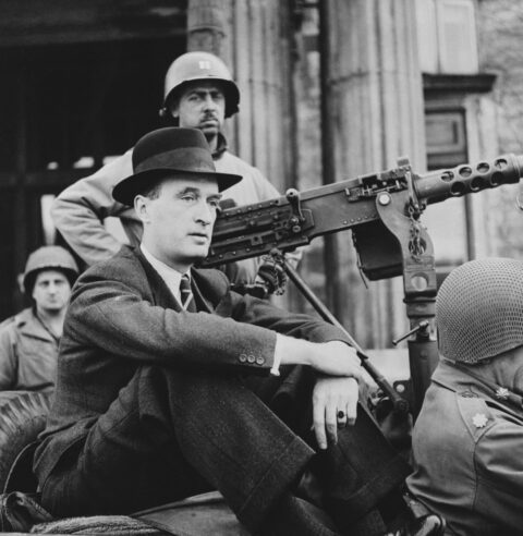 Alfried Krupp von Bohlen und Halbach sitzt auf der Rampe eines Militärfahrzeuges vor der Villa Hügel. Im Hintergrund zwei Soldaten, einer mit Maschinengewehr in der Hand.