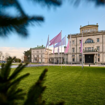 Villa Hügel mit wehenden rosa und weißen Fahnen im Vordergrund