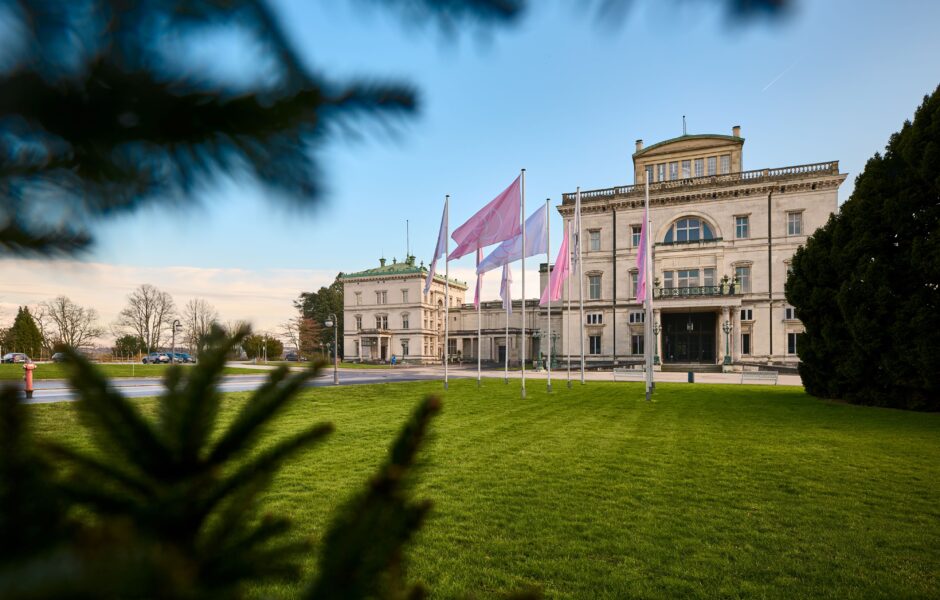 Villa Hügel mit wehenden rosa Fahnen im Vordergrund