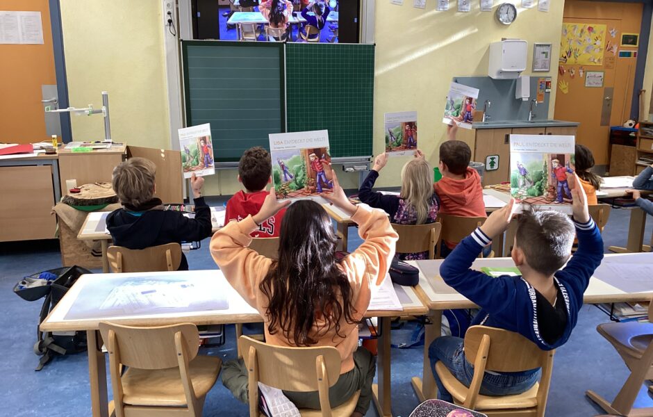 Pupils in a primary school class sit with their backs to the photographer and hold up books.