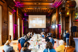 Viele Personen, die an einem Tisch sitzen während der Pressekonferenz "21 x 21. Die RuhrKunstMuseen auf dem Hügel" im Speisesaal der Villa Hügel