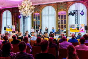 Blick in den Gartensaal, in dem fünf Personen auf der Bühne sitzen vor einem Publikum