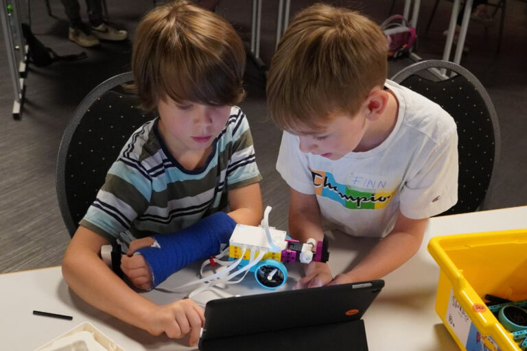 Zwei Jungs sitzen über einem Lego Roboter