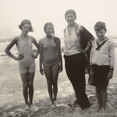 Drei Kinder mit ihrer Hauslehrerin im Strand