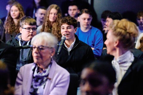 Eine Person, die in einer Menschenmenge in ein Mikrofon spricht.