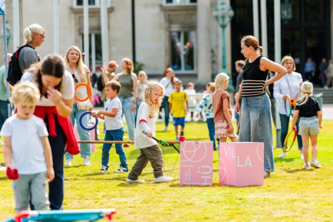 Erwachsene und Kinder die auf einer Wiese spielen
