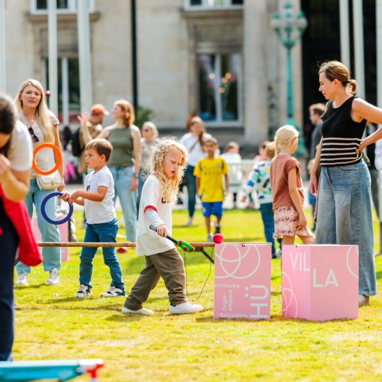 Erwachsene und Kinder die auf einer Wiese spielen