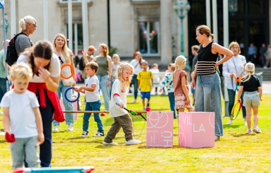 Erwachsene und Kinder die auf einer Wiese spielen